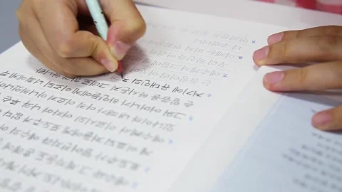 Close-up of a Child’s Hands Transcribing Bible Verses in Korean in a Notebook 動画素材 331074056