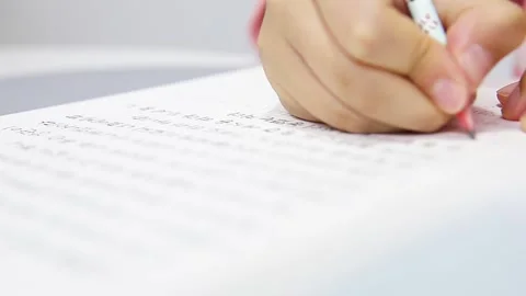 Close-up of a Child’s Hands Transcribing Bible Verses in Korean in a Notebook Stock Footage 331074062