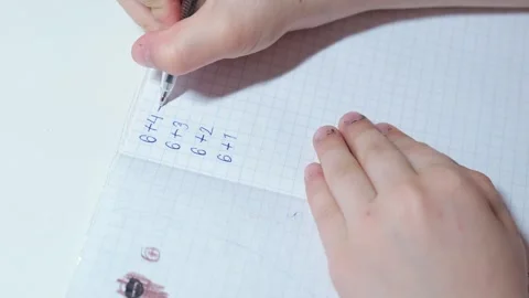 Close-up of a child’s hands writing simple arithmetic exercises Stock Footage 332159187