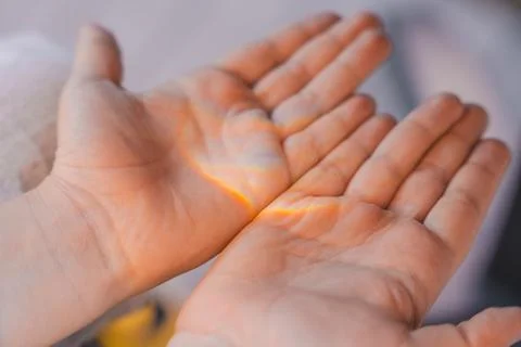 Close-up of childs open hands with soft rainbow light shining across the palms Stock Photos