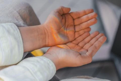 Close-up of childs open hands with soft rainbow light shining across the palms Stock Photos