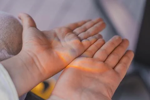 Close-up of childs open hands with soft rainbow light shining across the palms Stock Photos