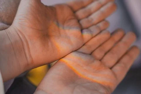 Close-up of childs open hands with soft rainbow light shining across the palms Stock Photos