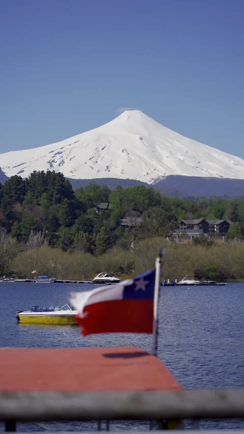 Close-up of Chile flag flying on a boat, behind the imposing Villarrica vol.. Stock Footage 289554275