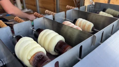 Close-up chimney cakes grilling over hot coals, traditional Hungarian pastry Stock Footage 322580856