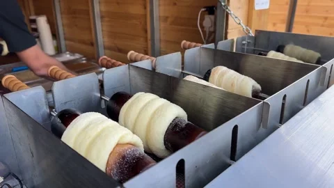 Close-up chimney cakes grilling over hot coals, traditional Hungarian pastry Stock Footage 322580861