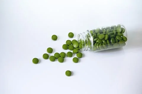 Close-up of chlorella tablets in a transporent bottle on a white background Stock Photos