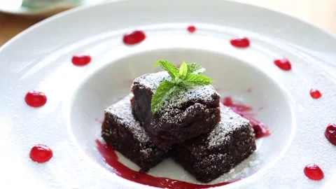 Close-up of Chocolate Brownie with Raspberry Sauce on spinning cake stand Stock Footage 276669607