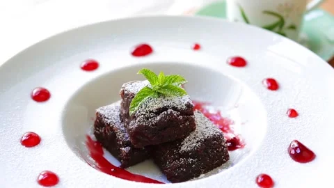 Close-up of Chocolate Brownie with Raspberry Sauce on spinning cake stand Stock Footage 276669610