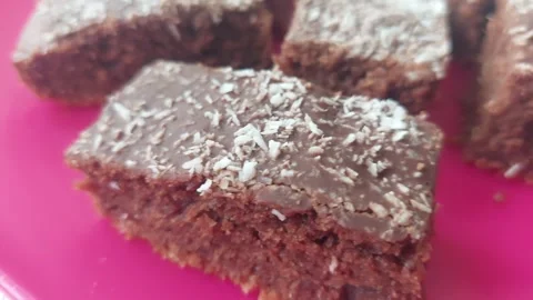 Close-up of a Chocolate Cake Slices with Coconut Sprinkles on a Pink Plate Stock Footage 333642314