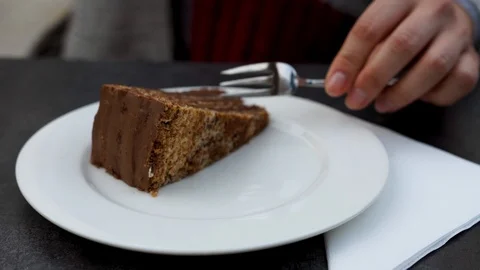 Close-up chocolate cake on white plate. Girl hand taking piece of cake by fork Video stock 121361680