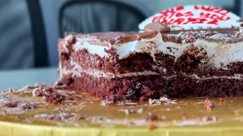 Close-Up of Chocolate Cream Cake Slice with Red Icing Message on Golden Board Stock Footage 333854821