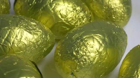 Close-up of chocolate Easter eggs wrapped in shiny golden foil rotating on .. Stock Footage 340072229