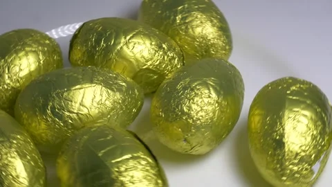 Close-up of chocolate Easter eggs wrapped in shiny golden foil rotating on .. Stock Footage 340072246