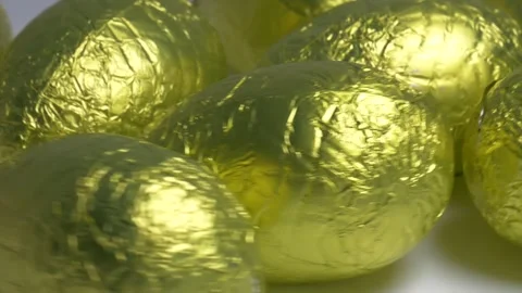 Close-up of chocolate Easter eggs wrapped in shiny golden foil rotating on .. Stock Footage 340072249