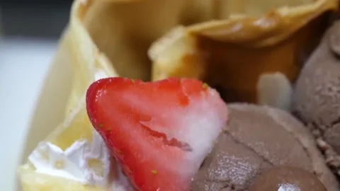 Close-up of Chocolate Ice Cream Scoop with Banana Slice in a Crepe Cone Stock Footage 345692402
