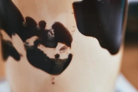 Close-up of chocolate syrup dripping down the side of a glass cup with coffee Stock Photos
