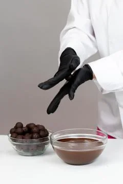 Close-up chocolatier rolling truffle candy between palms forming round shape Stock Photos