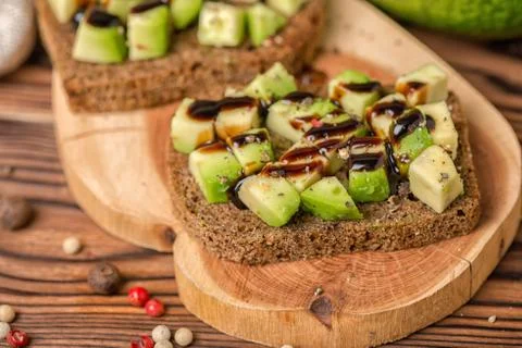 Close up of chopped avocado on rye bread toast decorated drizzled with sauce  스톡 사진