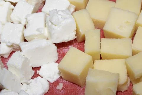 Close up of chopped cheese cubes on a red chopping board Photos