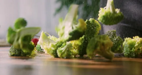 Close up of chopped wet broccoli florets falling down on wooden countertop Video stock 151089428