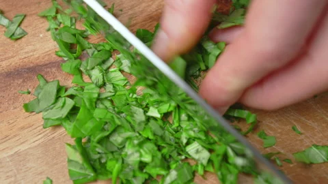 Close-up of chopping Basil Leaves with a chef knife on a cutting board in 4K. Stock Footage 145105615