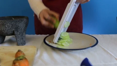 Close up of chopping cucumber with mandolin slicer,  handheld shot Stock Footage 124664323