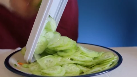 Close up of chopping cucumber with mandolin slicer,  handheld shot Stock Footage 124664324