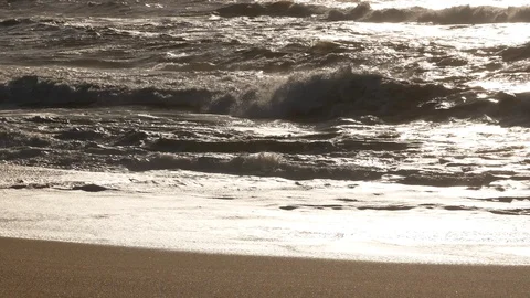 Close up choppy waves breaking on sandy beach with reflections on water surface Stock Footage 103286953