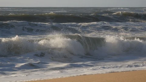 Close up of choppy white waves breaking on the sandy shore of empty beach Stock Footage 103284055