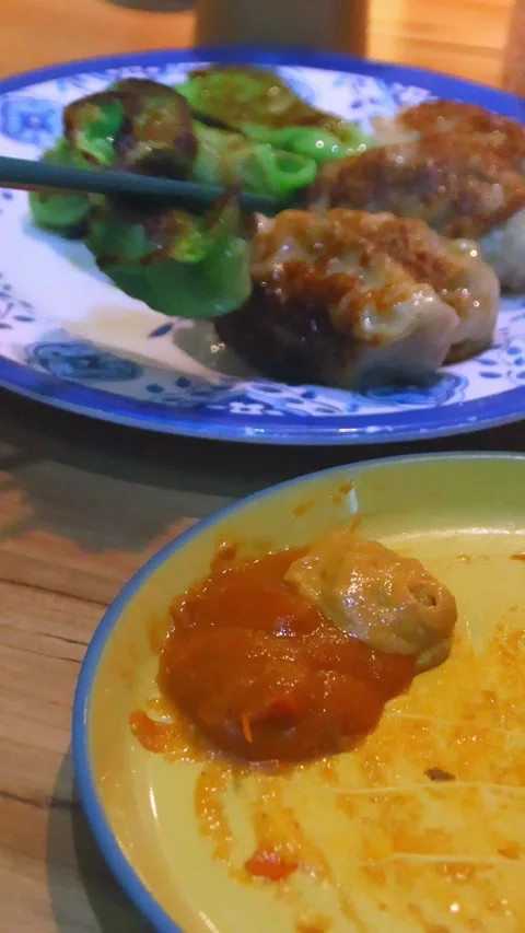 Close up of chopsticks dipping fried green spinach momo in chilli sauce  Stock Footage 332596935