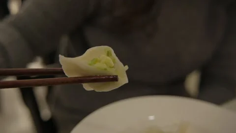 Close-Up of Chopsticks Holding Cut Dumpling with Vegetable Filling in Beijing Stock Footage 345892229