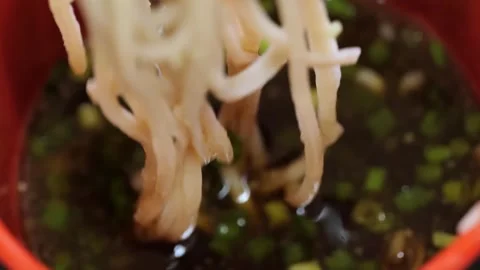 Close-up of Chopsticks Lifting Fresh Soba Noodles from Savory Dipping Sauce with Stock Footage 333524310