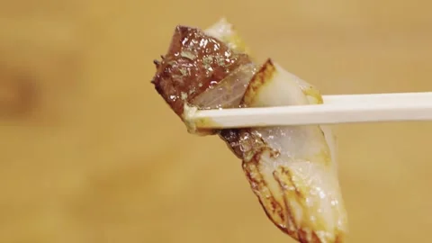 Close-up of Chopsticks Picking Up Grilled Wagyu Beef Skewer with Onions Stock Footage 337441122
