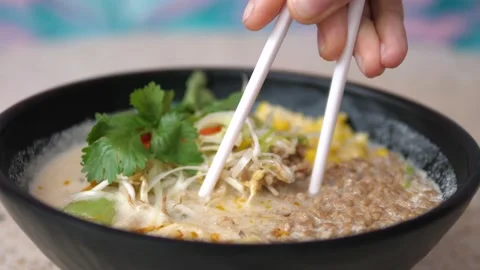 Close up of chopsticks pulling noodles out of vegan ramen soup with and showing Stock Footage 149796418