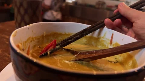 Close up of chopsticks pulling sweet and chili pepper out of vegan laksa soup Stock Footage 278445357