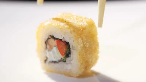 Close up of chopsticks taking portion of sushi roll on the table restaurant Video stock 105634101