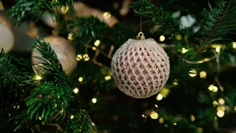Close-up of a Christmas bauble on a green tree with twinkling fairy lights Stock Footage 322632413