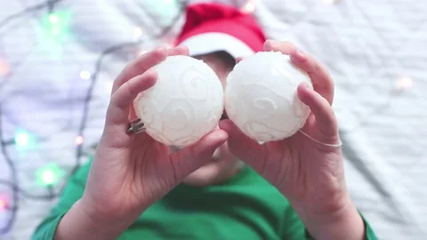 Close-up of Christmas decorations of white glitter balls in children's hands. Stock Footage 165384001