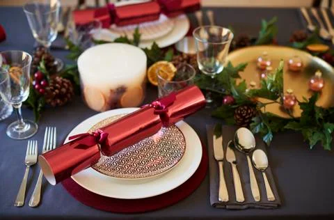 Close up of Christmas table setting with crackers arranged on plates and red Stock Photos