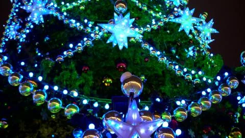 Close-up Christmas tree on square decorated with multi-colored garlands, balls Stock Photos