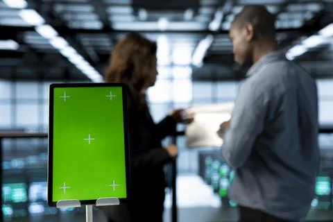 Close up of chroma key tablet next to workers supervising data center Foto stock