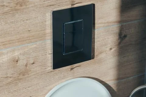 Close-up of a chrome dual flush button on a wall with wood-grain tiles Stock Photos