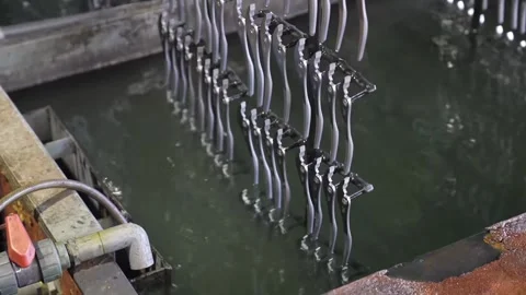 Close-up of chrome-plated pliers emerging from electroplating solution dripping Stock Footage 336682080