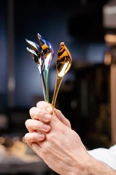 Close-up of chrome professional spoons of tools in the hands of a chef in Stock Photos