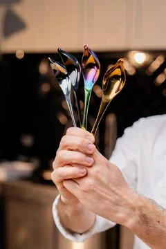 Close-up of chrome professional spoons of tools in the hands of a chef in Stock Photos