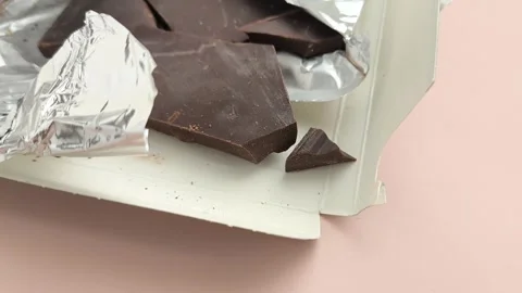 Close-up chunks of dark natural chocolate in foil packaging Stock Footage 324555127
