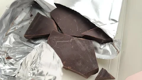 Close-up chunks of dark natural chocolate in foil packaging Stock Footage 324555133