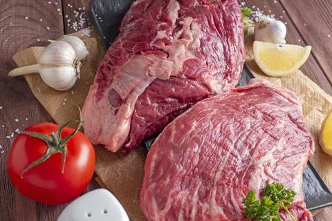 Close-up of chunks of juicy raw beef on parchment. Vegetables and spices arou Foto stock
