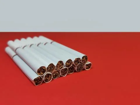 Close-up of cigarettes with a white filter lying in a stack on a red-white ba Stock Photos